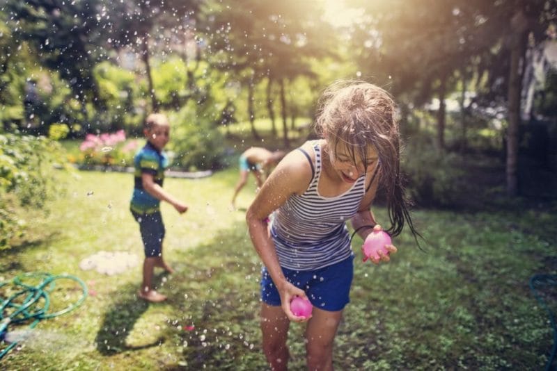 niños y niñas jugando a guerra de globos de agua
