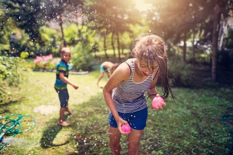 niños y niñas jugando a guerra de globos de agua