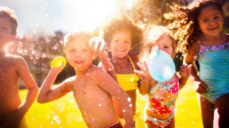niños y niñas jugando a globos de agua